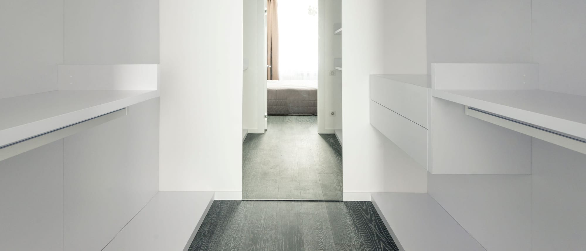 A bright dressing room with a run of full-height wardrobes and clothes hanging behind translucent doors