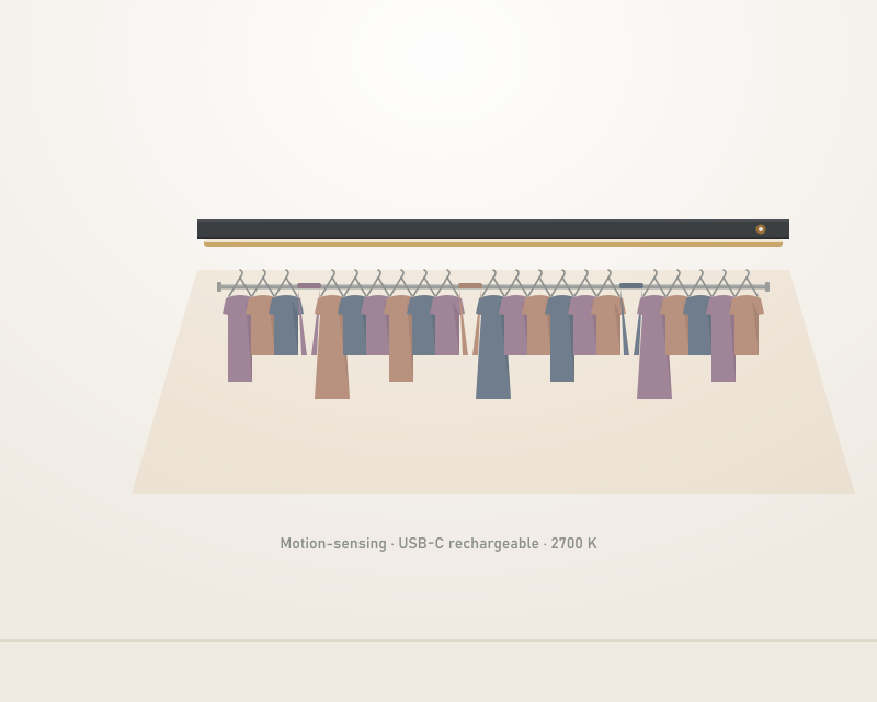 A slim aluminium LED strip clipped into a wardrobe top rail, casting light down over hanging clothes